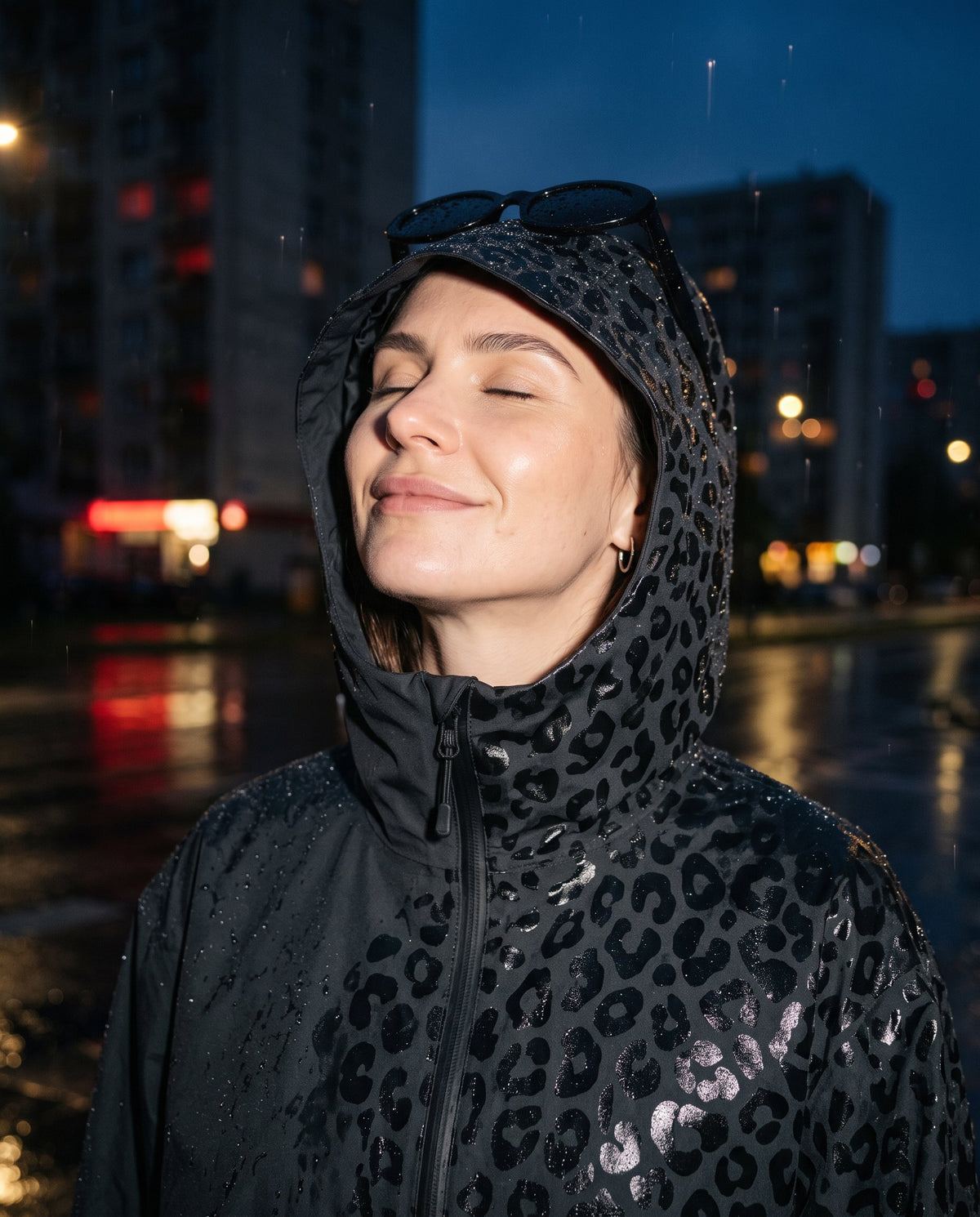 Kobieta w kapturze kurtki NIMBA z twarzą zwróconą do deszczu